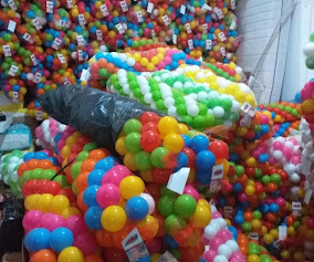 Anak memegang bola plastik warna-warni